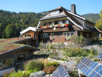 Naturhotel - Hoteltyp: BIO-Urlaubshotel - Haus Sonne im Sommer, im Vordergrund der Kräutergarten und Solarpanels. - Haus Sonne - das vegetarische Bio-Hotel